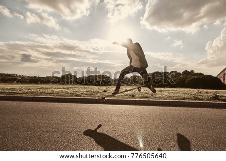 Hobby, extreme sports and recreational activity. Lifestyle portrait of young professional skateboarder practicing his skills, doing stunts using longboard on motorway. Patch of sunlight on asphalt