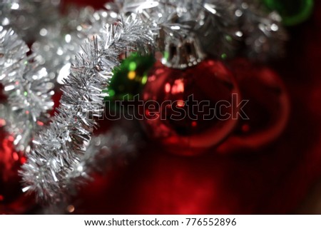 Red, green, silver and white Christmas decorations tinsel garland and ornaments on a soft Santa Claus background.