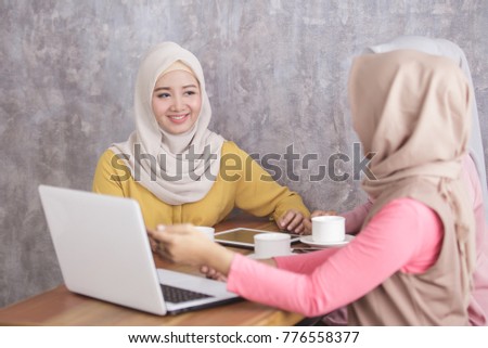 portrait of beautiful muslim women explaining project on laptop to her partner at coffee shop