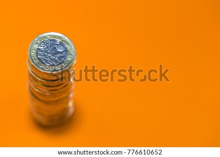 Stacked Pound Coins on a Bright Orange Background - Negative Copy Space Royalty-Free Stock Photo #776610652