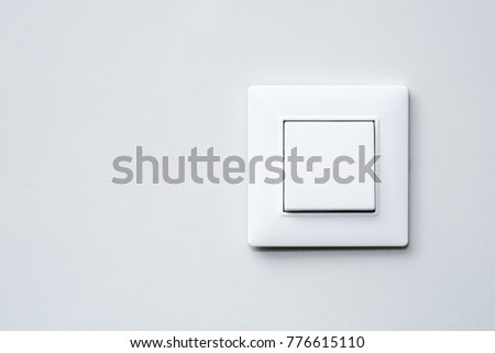 a light switch, a plastic mechanical switch of white color installed on a light gray wall. Royalty-Free Stock Photo #776615110