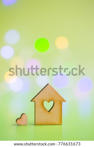 Wooden house with hole in form of heart with little heart on green bokeh background. Concept of sweet home.