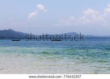 Landscape of the coast, turquoise sea and two boats with mountains in the background in Cahuita National Park, Costa Rica