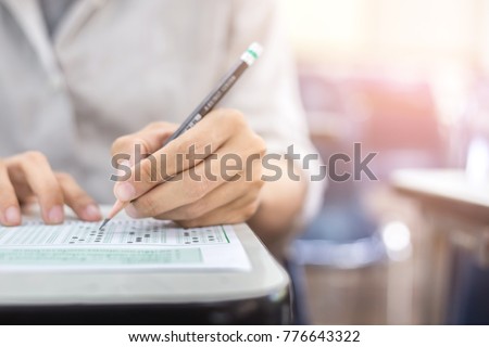 soft focus.high school or university student holding pencil writing on paper answer sheet.sitting on lecture chair taking final exam attending in examination room or classroom.student in casual Royalty-Free Stock Photo #776643322