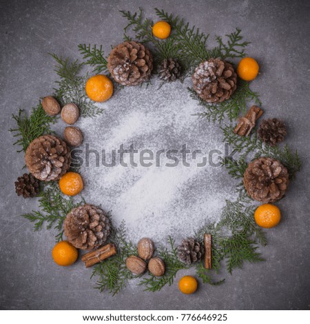 Christmas background. Christmas wreath with snow fir cones tangerines
spruce cinnamon nuts. Flat lay. Copy space.