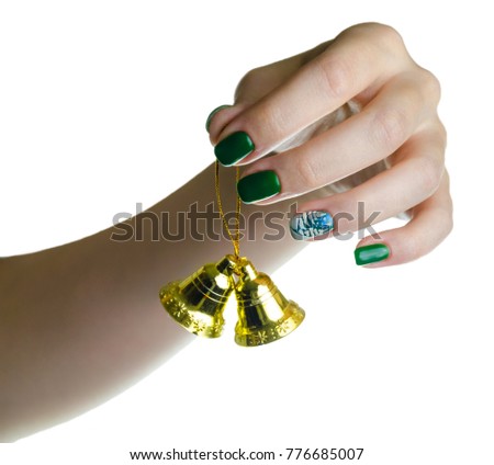 closeup girl hands with New Year's manicure. hanging golden, gold Jingle Bells. element of Christmas decorations. bell is symbol of winter holiday. art picture on the green nails