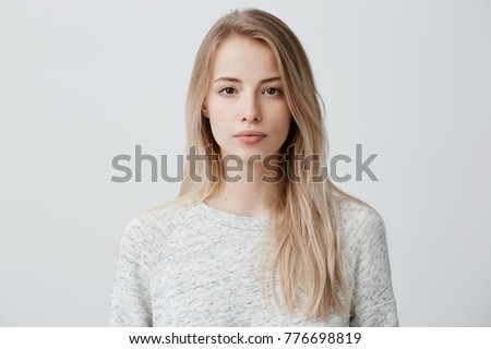 Confident good-looking beautiful woman with blonde dyed hair with healthy pure skin dressed in casual clothes looking seriously at camera. Youth and beauty concept Royalty-Free Stock Photo #776698819