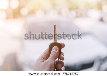 A man holding car keys with car on background