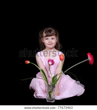 sweet little girl sitting with vase of spring flowers, isolated on black