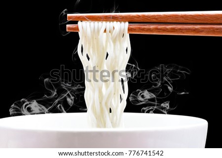 instant noodles in chopsticks on white bowl with smoke