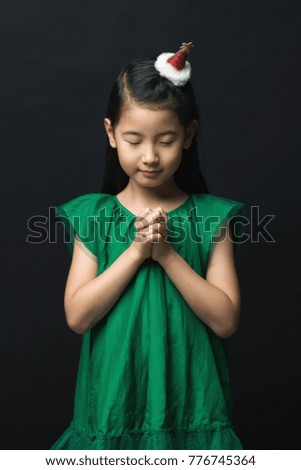 Cute Asian woman praying for Christmas with headdress on black background and gathering two hands Children