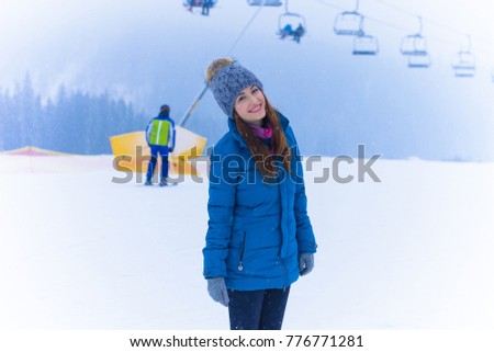 Young cute woman rests on a winter vacation in the mountains, a fun and beautiful winter time. A girl in a snow-covered forest and mountains. Active and joyful outdoor recreation