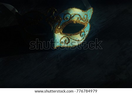 Image of elegant blue and gold venetian, mardi gras mask over dark background. Vintage filtered photo