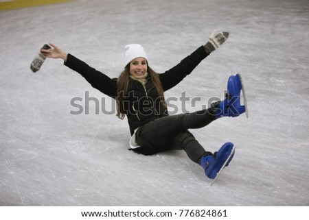 Young happy woman sitting on ice of a skating rink