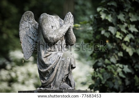Cherub without head. Damaged statue on old cemetery.