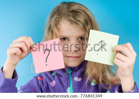 Girl holding stickers with question marks, Blue background