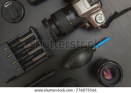 top view of work space photographer with dslr camera system, camera cleaning kit and camera accessory on black table background