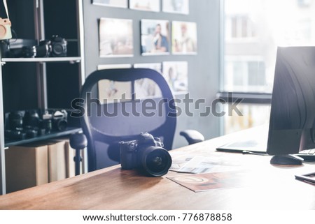 Interior of modern apartment with table and chair in modern room. Professional camera and notebook computer situating on it. Design concept