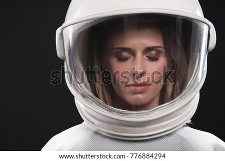 Keep calm. Close-up portrait of attractive spacewoman wearing helmet and protective costume is standing with closed eyes. Isolated background. Cosmos concept