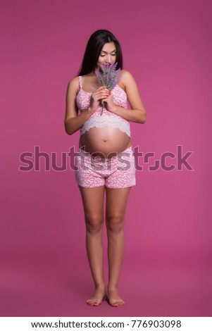 Cute pregnant girl in pink pajamas with flowers