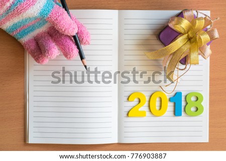Men reading notepad with glove and gift box, number 2018 on wood board background.using wallpaper for education, business photo for happy new year image copy space.