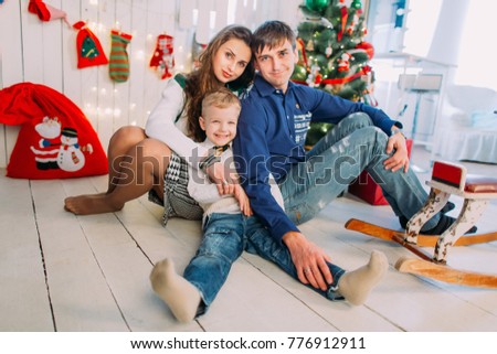 New Year's picture of happy family on background of Christmas decorations. Smiling mother and father with their son sitting and having fun 