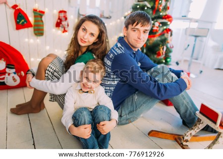 New Year's picture of happy family on background of Christmas decorations. Smiling mother and father with their son sitting and having fun 