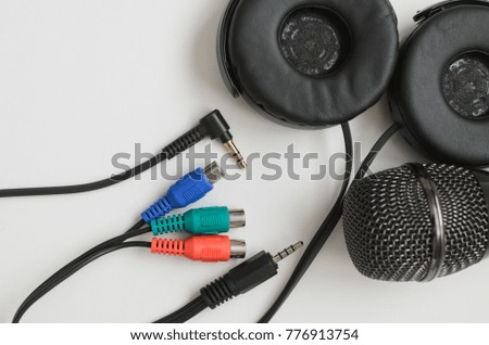Black microphone , black headphones and multi-colored jack plug isolated on white background.