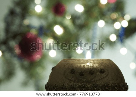 Candle in the New Year style against the background of a tree with decorations.