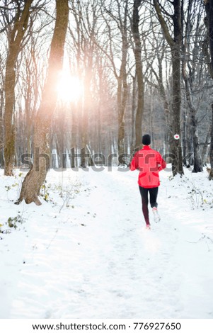 Determined young man running away from camera through a snow covered forest.