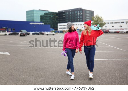 Two happy hipster girls with skateboards outdoors
