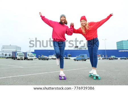 Two happy hipster girls having fun with skateboards outdoors