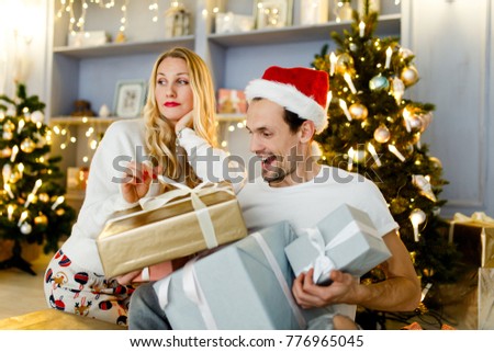 Photo of happy couple in Santa cap with gift in box