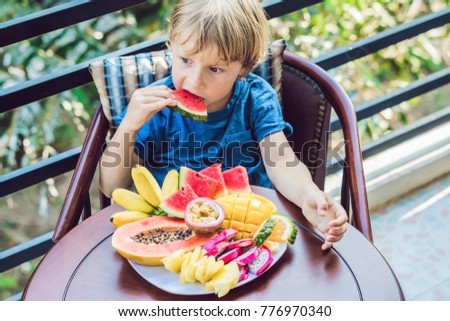 The boy is eating different fruits on the terrace.