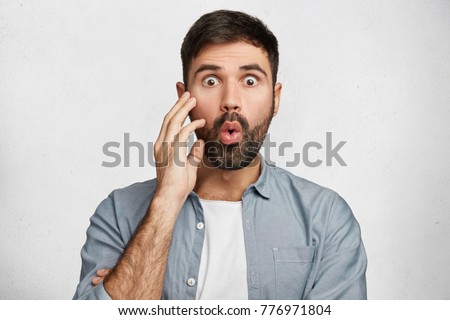 Omg what I see! Bugged eyed bearded male model stares at camera, can`t believe in such high prices, wants to renew wardrobe but being short of money. Hush reaction and great surprisment concept Royalty-Free Stock Photo #776971804