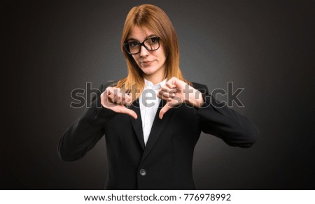 Young business woman making bad signal on dark background