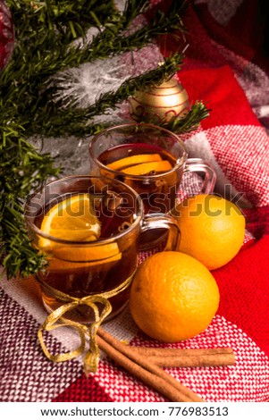 Tea with orange, oranges, plaid plaid, cinnamon on the background of a Christmas tree in the New Year