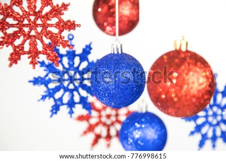 Closeup view of different Christmas ornaments isolated on white background. Colorful blue and red shiny toys hanging on silver ropes. Horizontal color image.