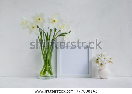 Mockup with a white frame and white daffodils in a vase on a light background