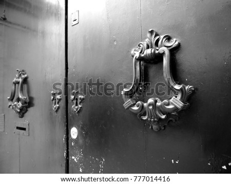 Door, detail. Manhole covers, keyholes, doorknockers. Black and white photo.