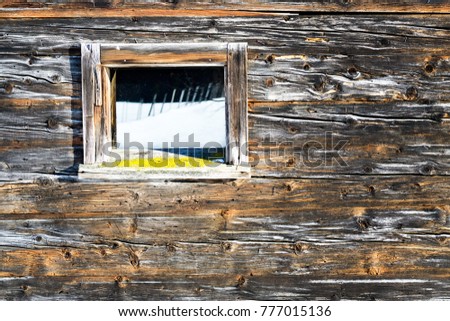 Vintage window of old wooden cabin mirrors winter landscape. Wooden rustic background.
