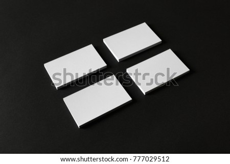 Photo of four blank business cards stacks on black paper background.