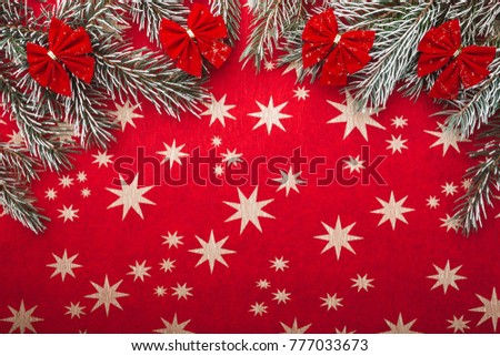 Christmas fir branches with bows, on red stared paper background, view from top, above, with space for Xmas text wish. 