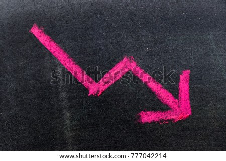 Red color hand drawing chalk in arrow down shape on black board background (Concept of stock decline, down trend of business, economy)