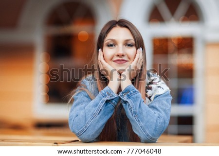 Close up portrait of a beautiful blonde girl Hand Lean Face sitting outdoor in cozy cafe in town. Pretty young model looking at camera and smiling