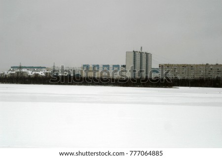 City landscape, houses on the shore of the ice lake. Snowy winter holiday background