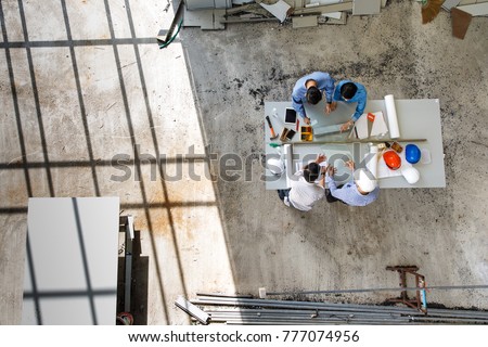 Four engineers in team making a discussion at construction site with several color helmets, taken from  bird eye views or top view