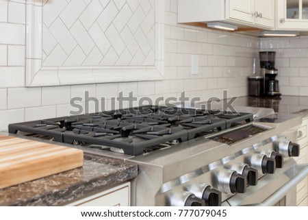 Stainless steel gas stove top with gray granite counter top and subway tile backsplash , vintage style cabinets Royalty-Free Stock Photo #777079045