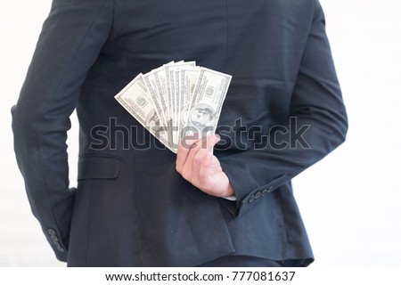Closeup of businessman hiding money on back.