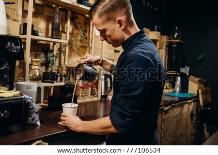 Handsome barista preparing cup of coffee for customer in coffee shop. Retro picture with little noise. 